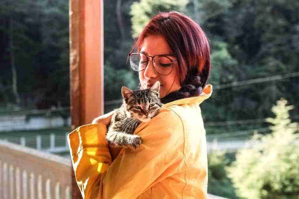 young woman carrying a contented tabby cat over her shoulder