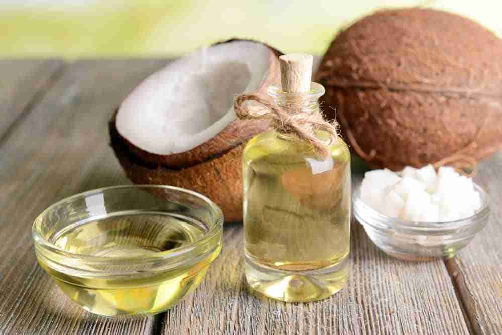 a scene of a wooden table with a bottle of coconut oil and coconut on top