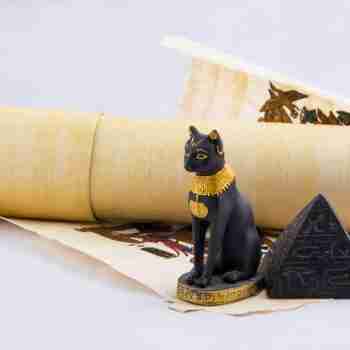 a papyrus parchment, decorative pyramid paperweight and statuette of an egyptian cat