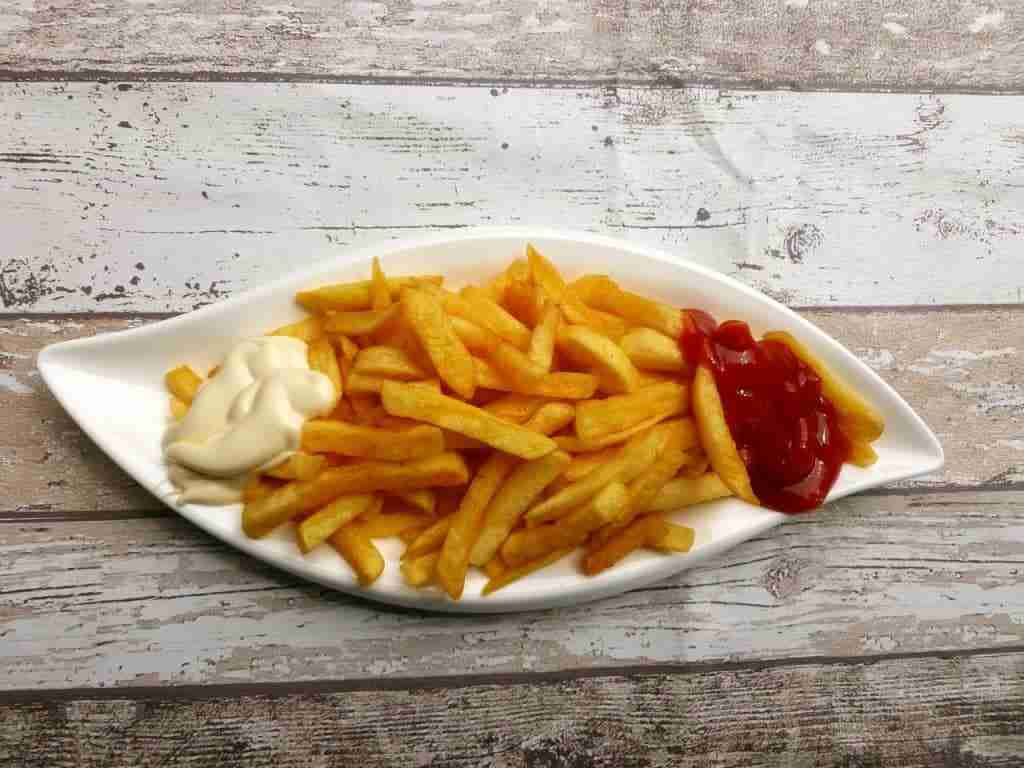 a plate of french fries with mayo and ketchup
