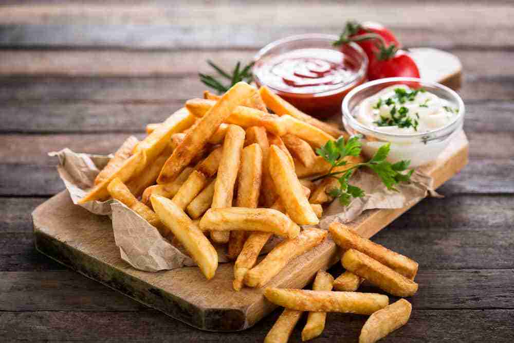 a platter of french fries served with dishes of tomato sauce and mayo