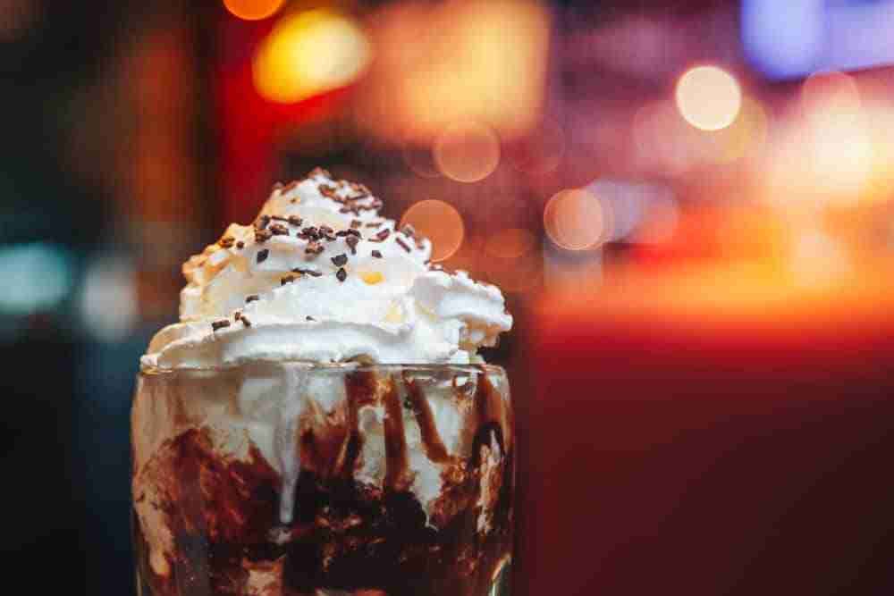 a close up of a chocolate sundae topped with whipped cream and chocolate sauce
