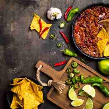 an overview of a pan of chili with tortilla and a chopping board with green chili