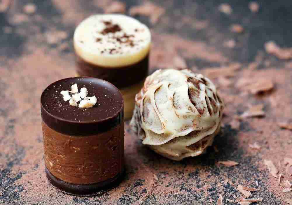 three hand made chocolates on chocolate dusted counter