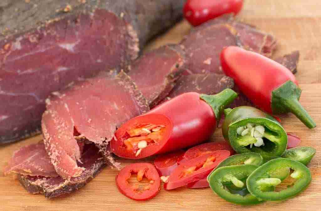 a close up of slices of dried beef with chili peppers